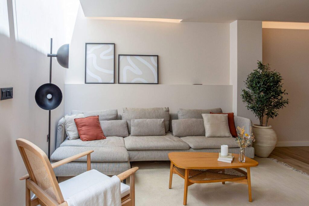Un salón mediterráneo elegante con techos altos, paredes blancas con microcemento o piedra caliza, sofás de lino en tonos neutros y mesas de mármol o madera de roble envejecida.