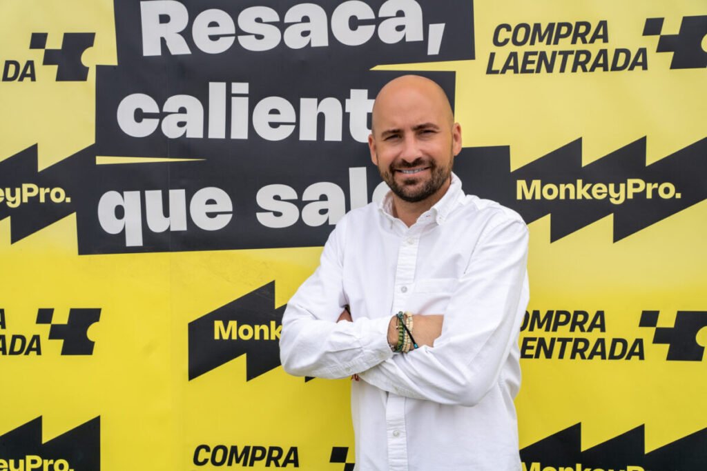 Alberto Vergara posando junto a los logos de MonkeyPro y compralaentrada.